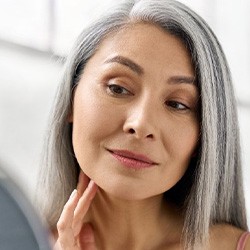 Patient in Garland looking in a mirror with dentures