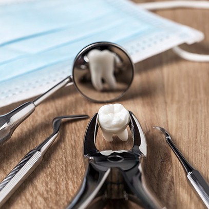 Extracted tooth held by forceps reflected in dental mirror