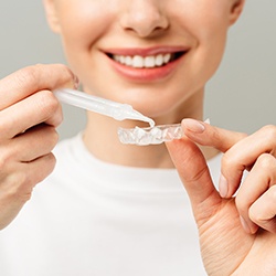 Nose-to-chest view of woman inserting gel into whitening tray
