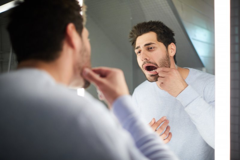 Patient looking at a loose tooth in the mirror