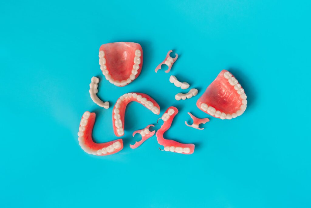 Bird's eye view of dental bridges and an assortment of full and partial dentures on an electric blue background