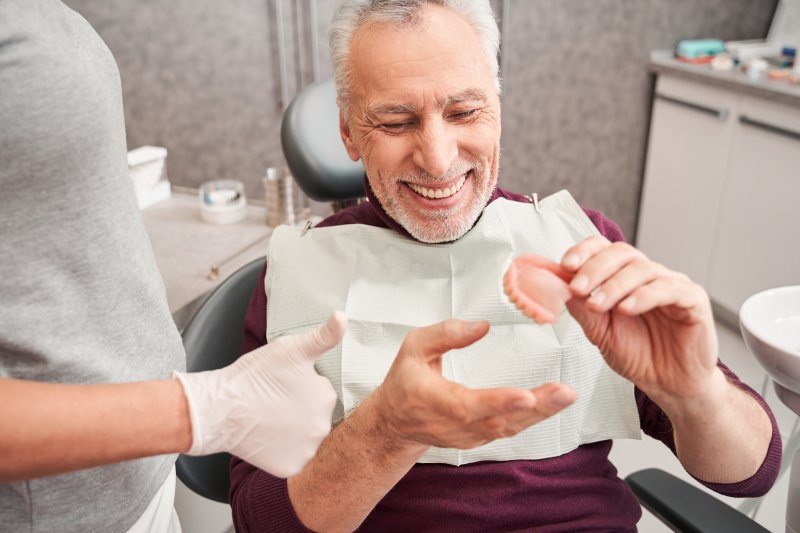 A dentist showing dentures to an older man